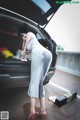 A woman in a gray dress standing next to a car.