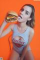 A woman in a bathing suit eating a hamburger.