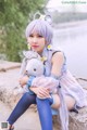 A woman sitting on a rock holding a stuffed animal.