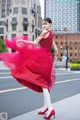 A woman in a red dress is dancing in the street.