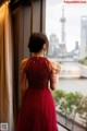 A woman in a red dress looking out a window.