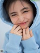 A young girl in a blue hoodie smiles at the camera.