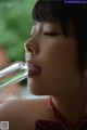 A woman is drinking from a glass bottle. 