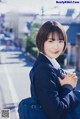 A young woman in a school uniform holding a blue bag.