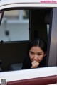 A woman sitting in the driver's seat of a car looking out the window.