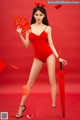 A woman in a red bathing suit holding a red envelope.