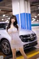 A woman in a silver dress standing in front of a car.