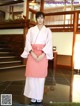 A woman in a pink kimono standing in a lobby.