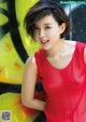 A woman in a red dress posing in front of a graffiti wall.