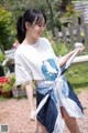 A woman in a white shirt and blue skirt holding a white umbrella.