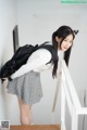 A woman in a school uniform with a backpack leaning against a wall.