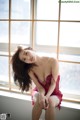 A woman in a red lingerie sitting on a window sill.