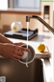 A person is pouring water into a bowl in a kitchen sink.