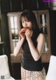 A young woman eating a piece of food in a room.