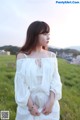 A woman in a white dress standing in a field.