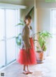 A woman standing in front of a window next to a plant.