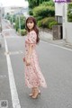 A woman in a pink dress is standing in the middle of the street.