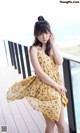 A woman in a yellow dress standing on a balcony.