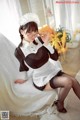 A woman in a maid outfit sitting on a bed.