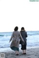 Two women walking on the beach holding hands. 