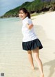 A young woman in a school uniform running on the beach.