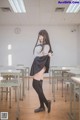 A woman in a school uniform standing in a classroom.