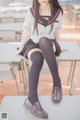 A woman sitting on top of a table in a classroom.