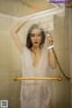 A woman standing in a shower holding a shower head.