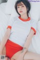 A woman in a white shirt and red skirt laying on a bed.