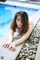 A young woman laying on the edge of a swimming pool.