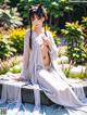 A woman in a white kimono sitting on a bench in a garden.