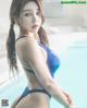 A woman in a blue bikini standing next to a pool.