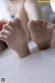 A close up of a doll's feet on a bed.