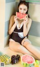 A woman in a black and white bathing suit eating a watermelon.