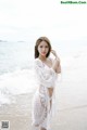 A woman in a white dress standing on a beach.