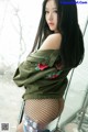 A woman in a green jacket and fishnet stockings posing for a picture.