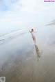 A woman in a blue bikini standing on a beach.