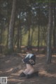 A woman sitting on the ground in the woods.