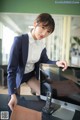 A woman in a business suit sitting at a desk with a computer.